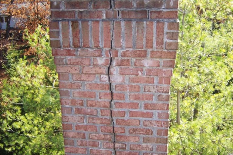 Brick chimney with a long crack and a metal cap, chimney leak for Charlotte, NC homes from Smoke Alert